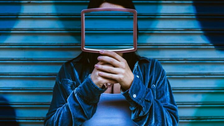 man covering face with mirror