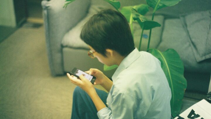 Person using a smartphone while sitting on the floor.