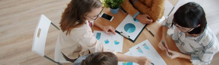 Diverse team collaborating around a table with charts.