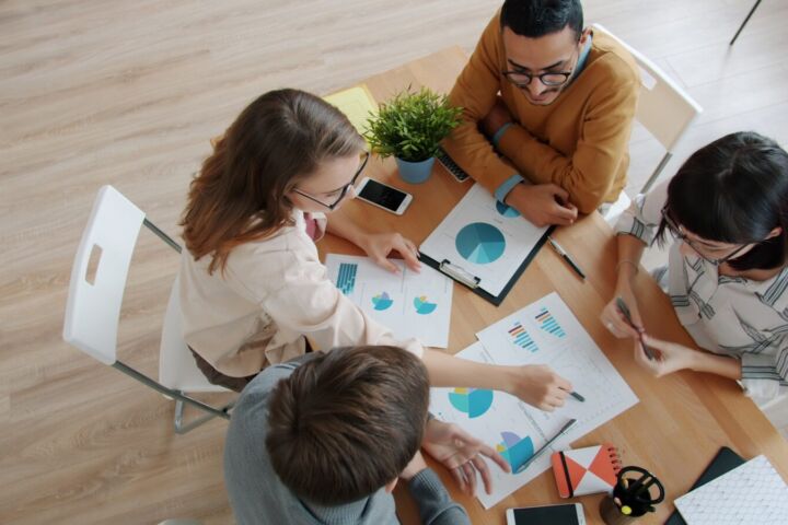 Diverse team collaborating around a table with charts.