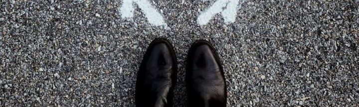 feet on asphalt between two directional arrows
