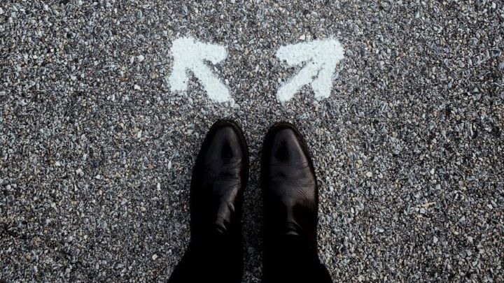 feet on asphalt between two directional arrows
