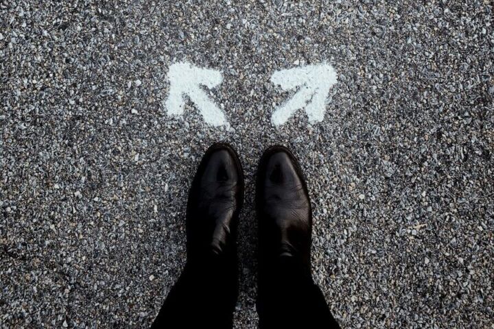 feet on asphalt between two directional arrows