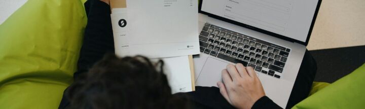 A person sitting on a bean bag chair working on a laptop
