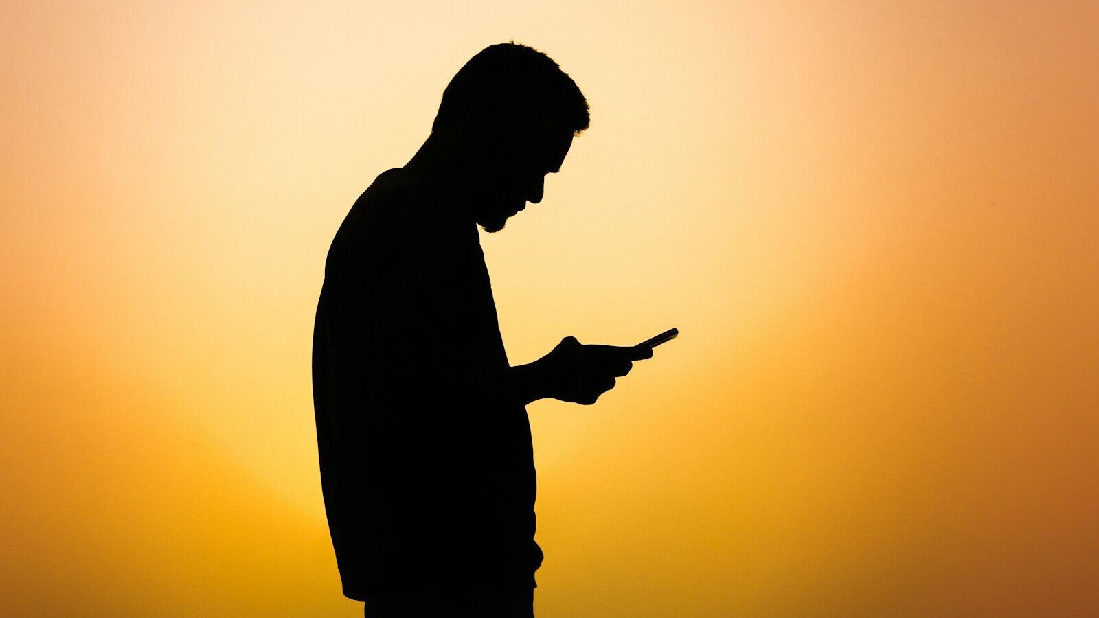 a silhouette of a man using a cell phone