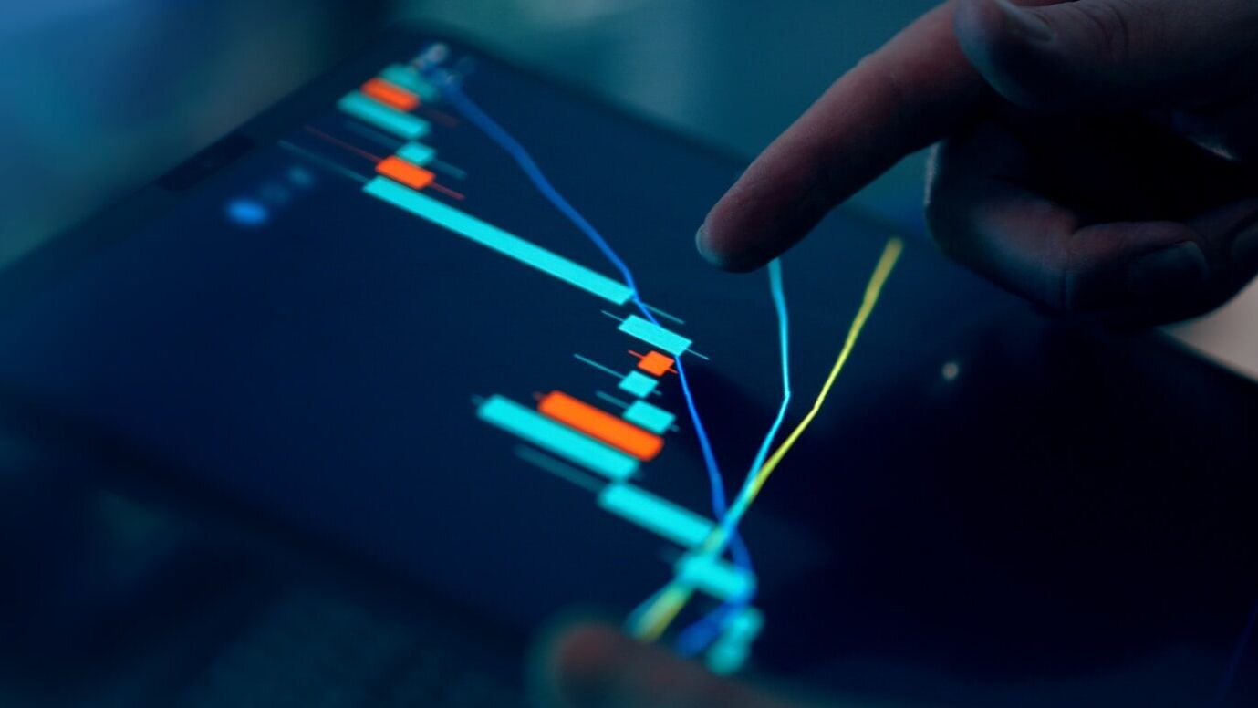Fingers interacting with a stock market graph on a tablet
