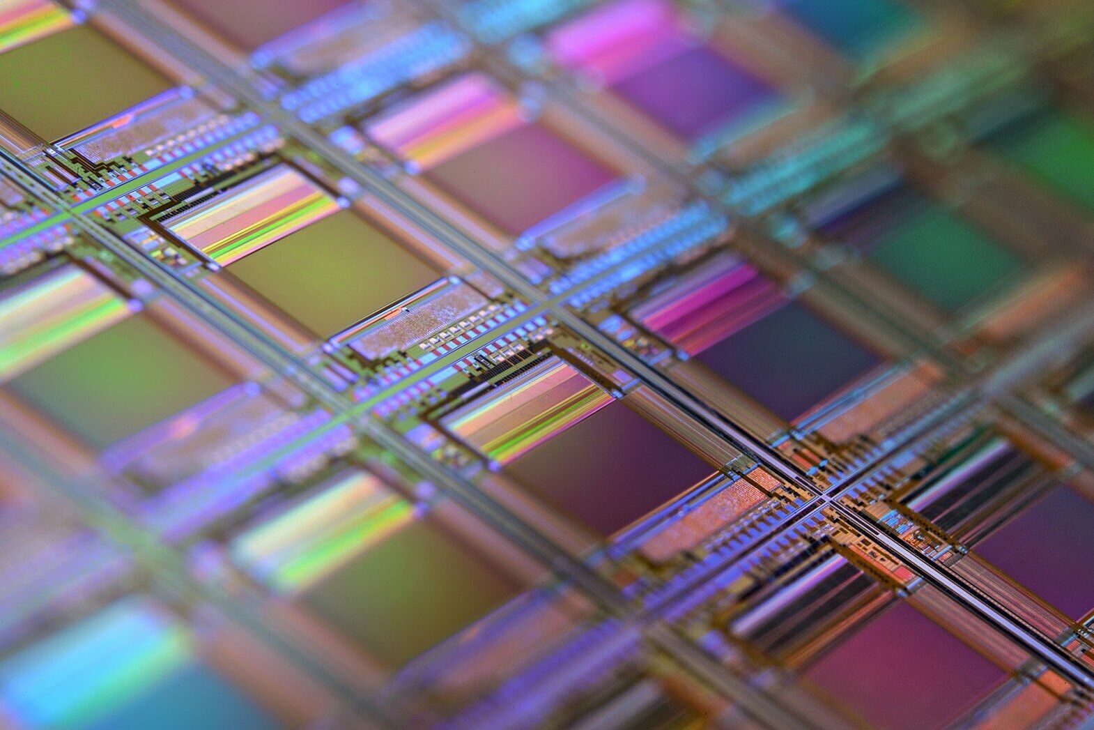 A silicon wafer with a grid of iridescent microchip dies under shallow focus
