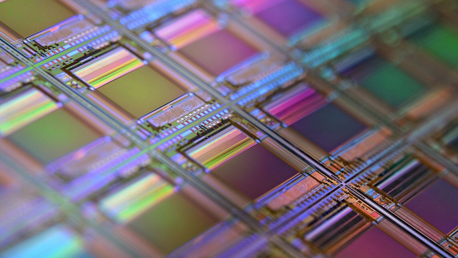 A silicon wafer with a grid of iridescent microchip dies under shallow focus