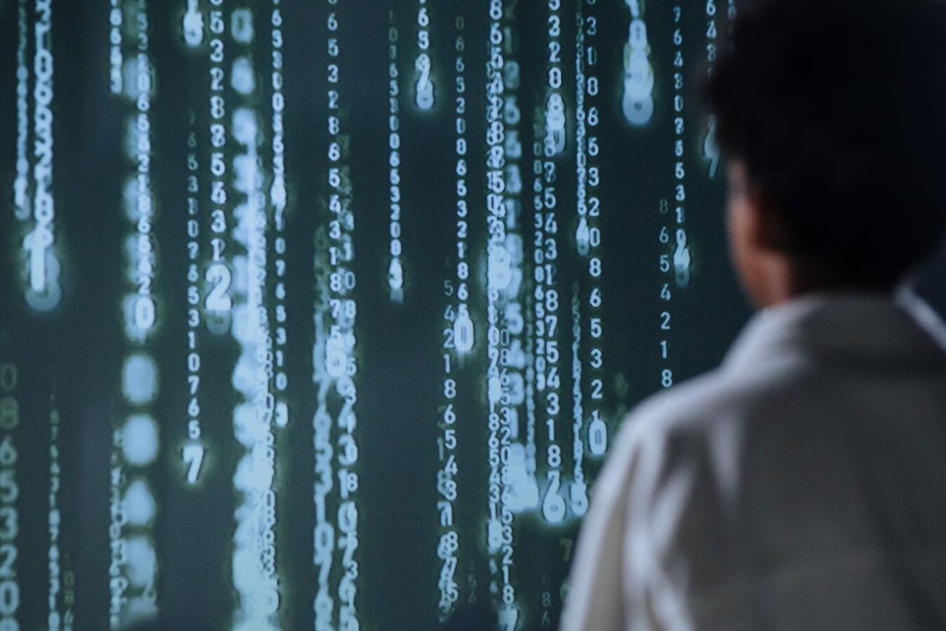 An individual viewing glowing numbers on a screen, symbolizing technology and data.