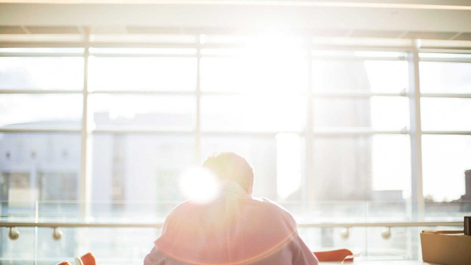 man sitting on chair in front on window during daytime