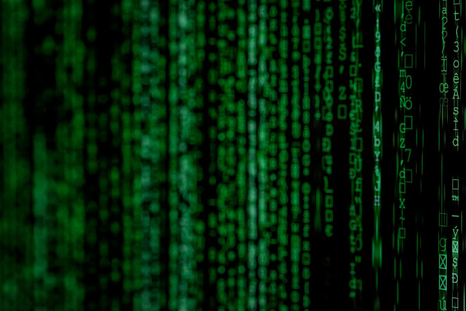 Vertical columns of glowing green digital code against a dark black background
