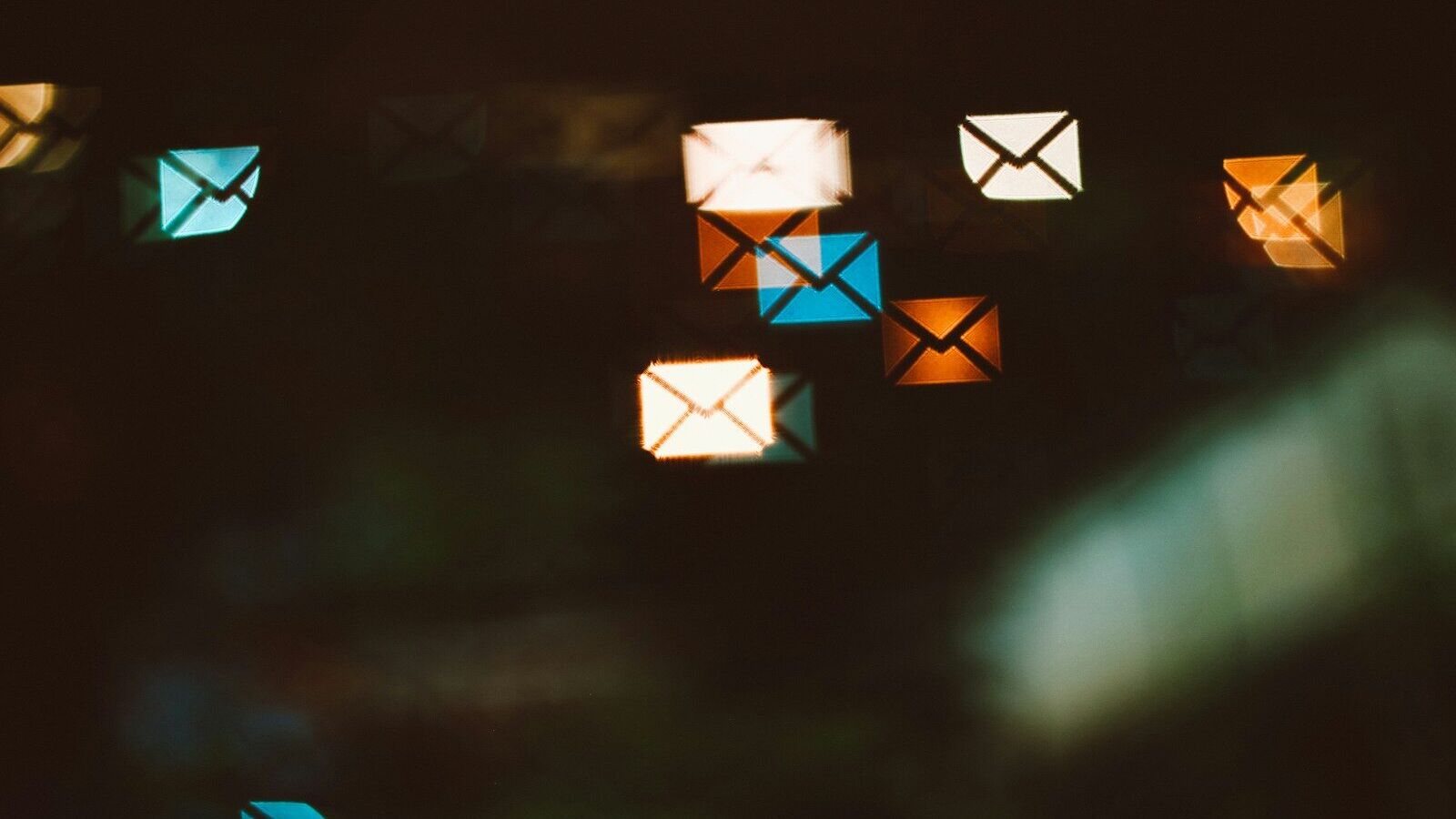 Envelope shaped bokeh lights in blue, orange, and white against a dark background