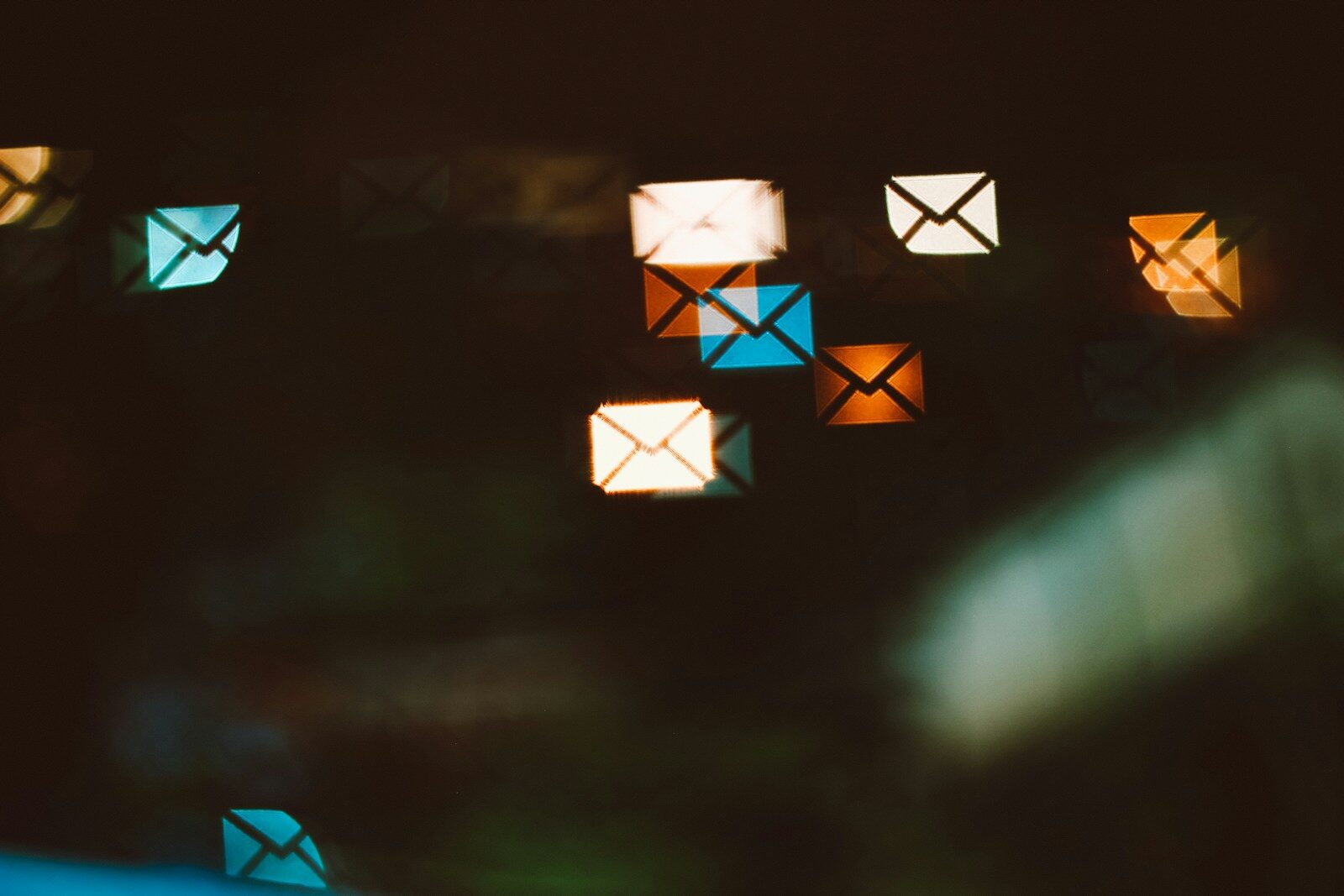 Envelope shaped bokeh lights in blue, orange, and white against a dark background
